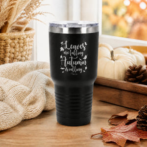 Black 30oz engraved Tundra tumbler engraved with “Leaves Are Falling Autumn Is Calling” in a sunlit autumn leaf trail…