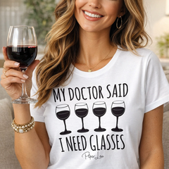 Woman wearing a white t-shirt with a humorous wine-themed graphic and text, holding a glass of red wine.