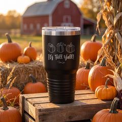 Black 30oz engraved Tundra tumbler engraved with “It's Fall Y'all Pumpkins” in a golden-hour pumpkin patch lifestyle